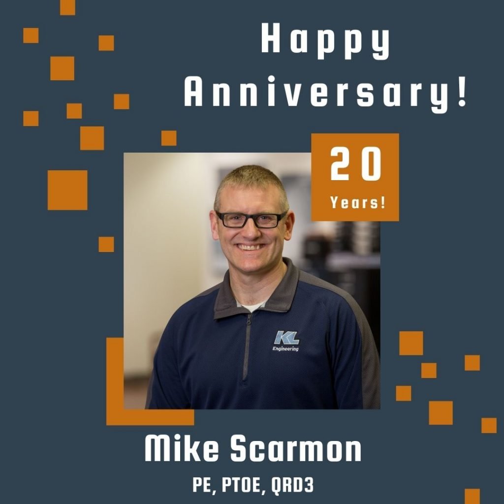 Photo of Mike Scarmon framed by a navy background with orange scattered boxes and Happy Anniversary text.