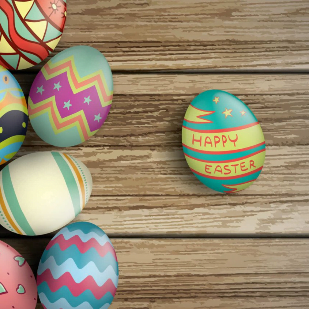 Colorfully painted eggs on a wooden background with 'Happy Easter' written on one.