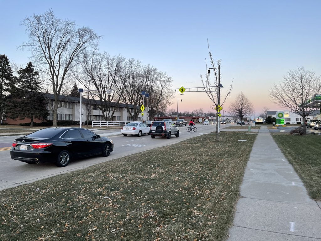 City of Sun Prairie's Rectangular Rapid Flashing Beacon (RRFB) signal and crosswalk with cars stopped for a bicyclist.