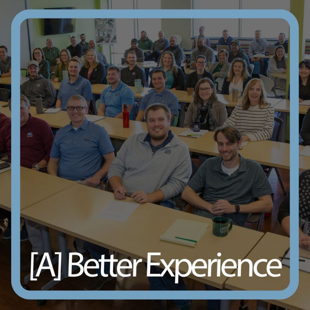 Graphic showing a faded photo of a group of KL employees in a meeting with '[A] Better Experience' in white text overlaid.