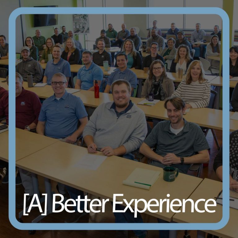 Graphic showing a faded photo of a group of KL employees in a meeting with '[A] Better Experience' in white text overlaid.