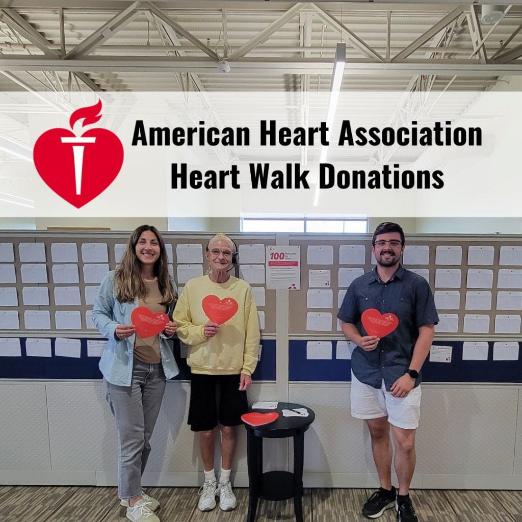 Photo of the three people mentioned in the post, holding red donation hearts, standing up against a wall covered with envelopes with American Heart Association logo and 'Heart Walk Donations' title.