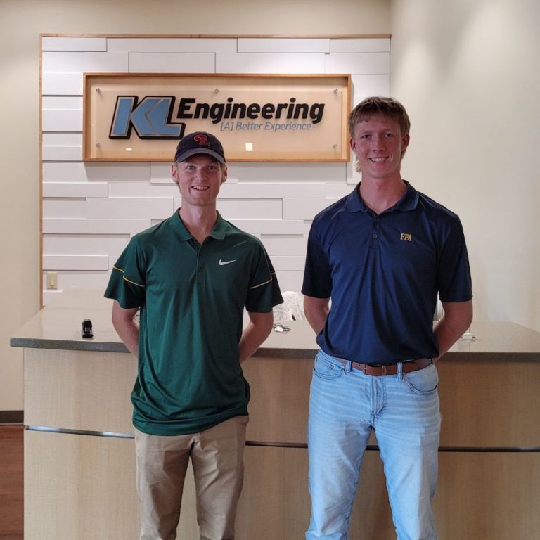 Photo of Cade and Dillon standing in our reception area in front of the KL Engineering sign.