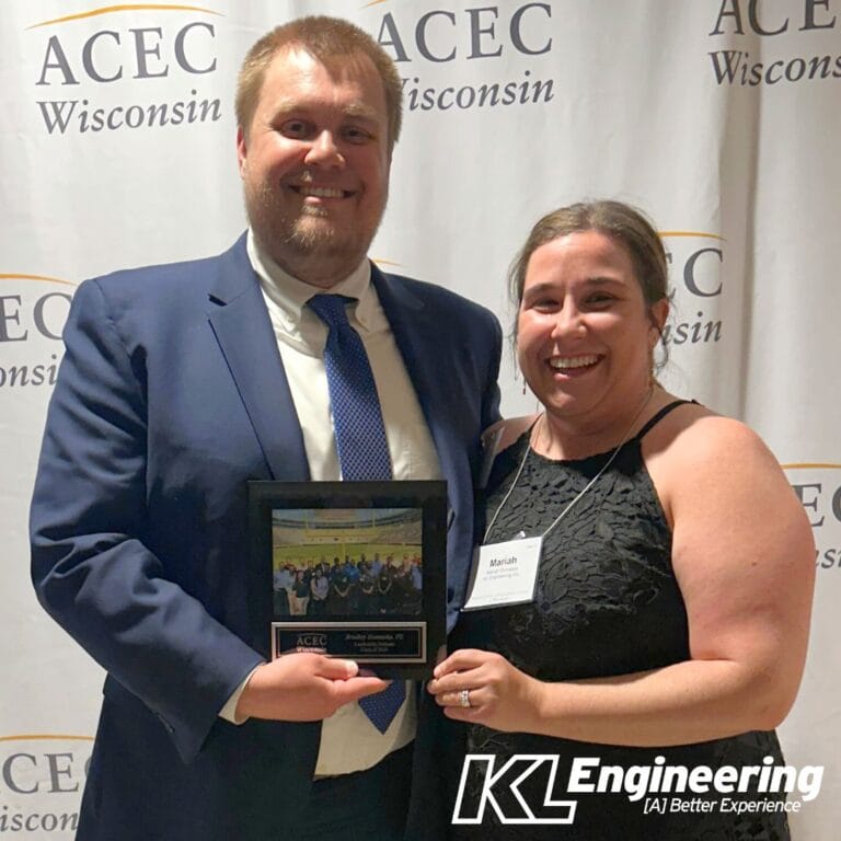 Photo of Brad and his wife posing with his award plaque.