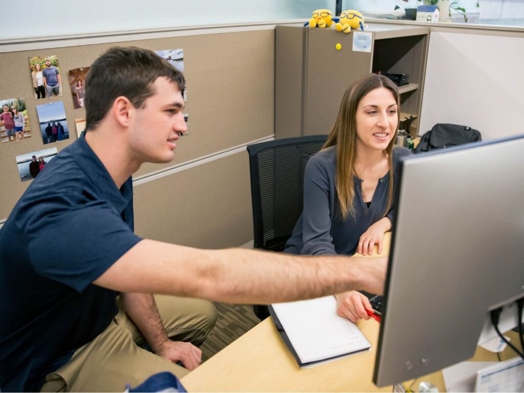 Two employees collaborating on a project at a desk.