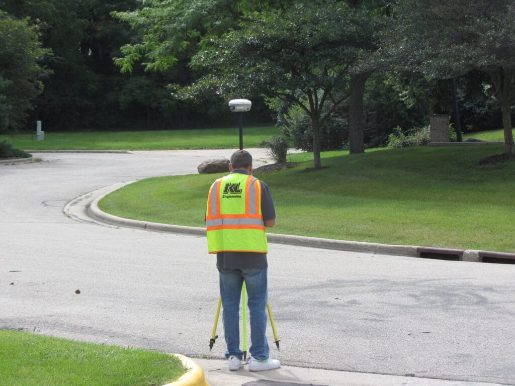Photo of employee surveying in a grassy green residential area.