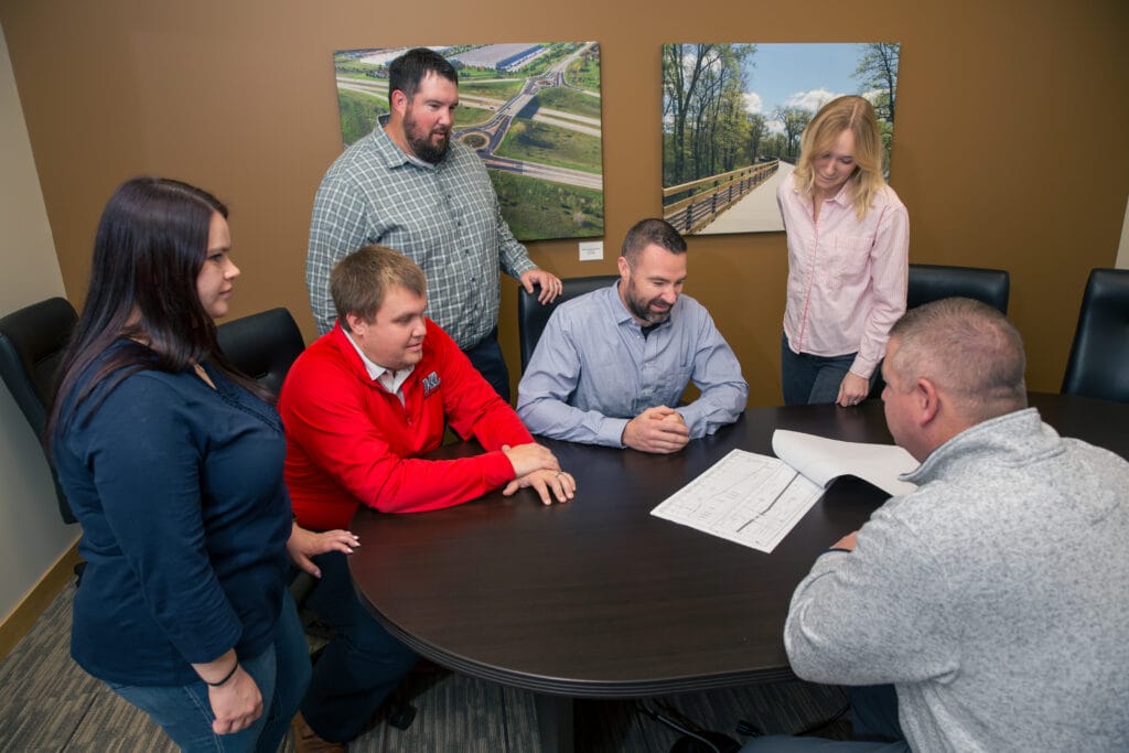 Team members sitting around a table discussing as set of plans.