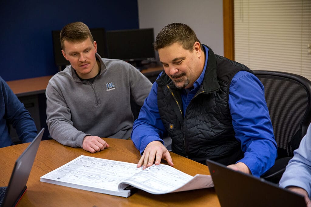 Two employees looking at a set of plans together in a meeting room.