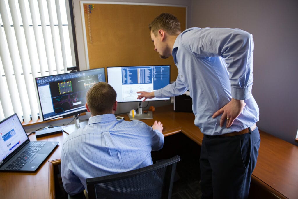 Two employees in an office working together on the computer.