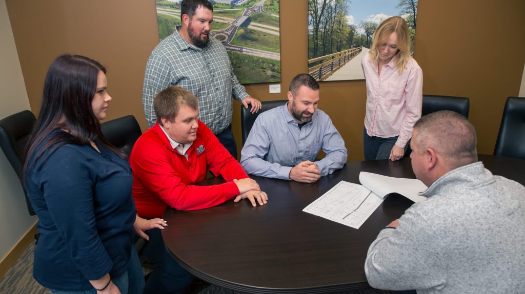 Team members sitting around a table discussing as set of plans.