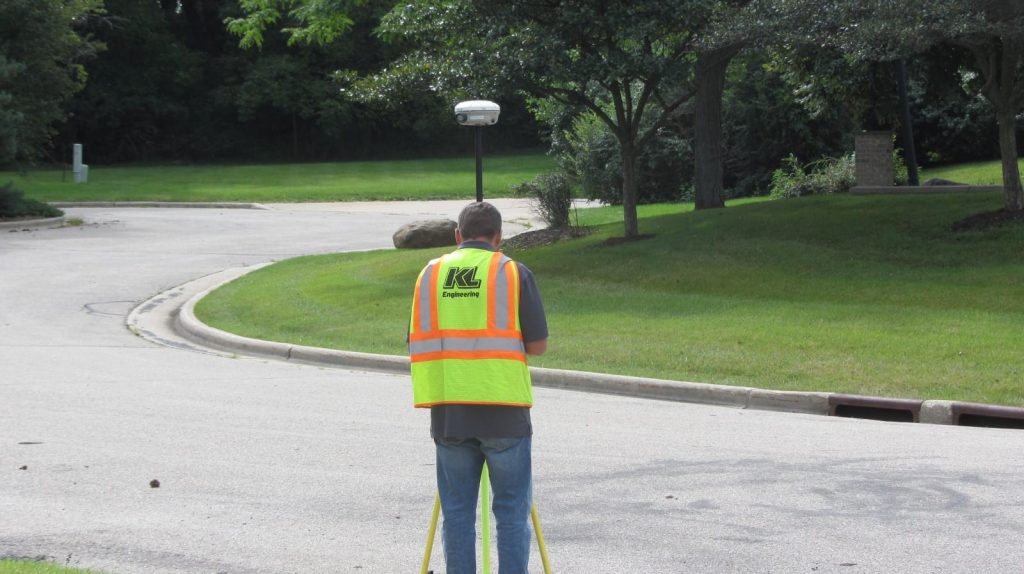 Photo of employee surveying in a grassy green residential area.
