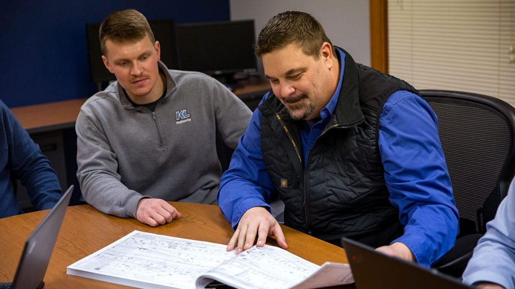 Two employees looking at a set of plans together in a meeting room.