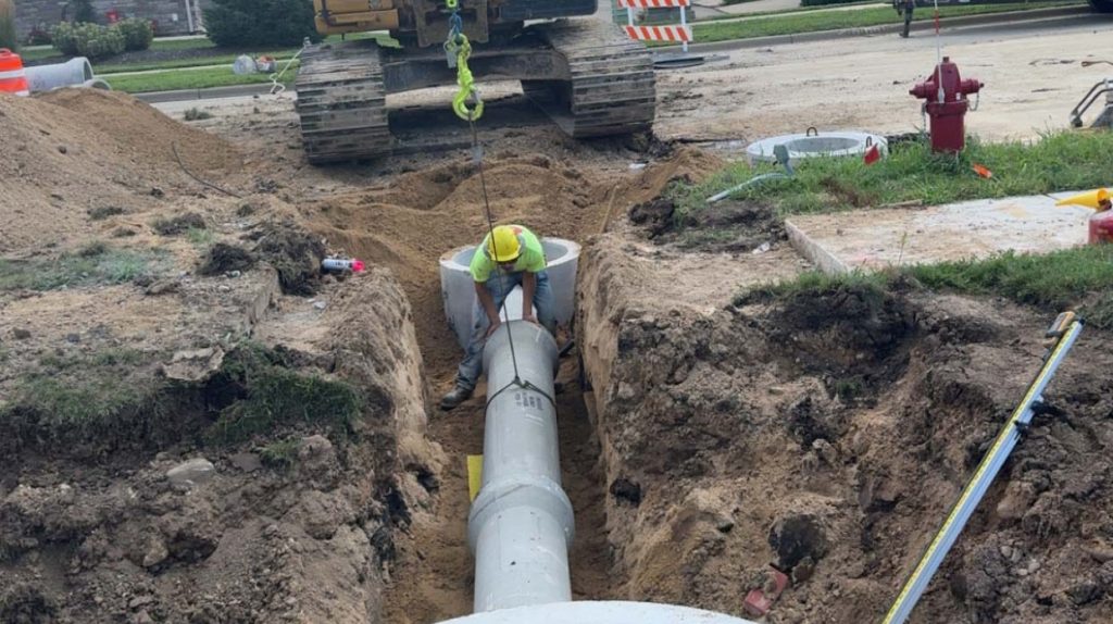 Construction workers installing a pipe underground in a residential area.